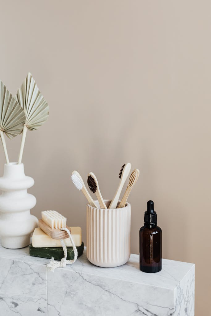 Hi there! Welcome to your Wellness journey. Collection of bamboo toothbrushes and organic natural soaps with wooden body brush arranged with recyclable glass bottle with natural oil and ceramic vase with artificial plant
