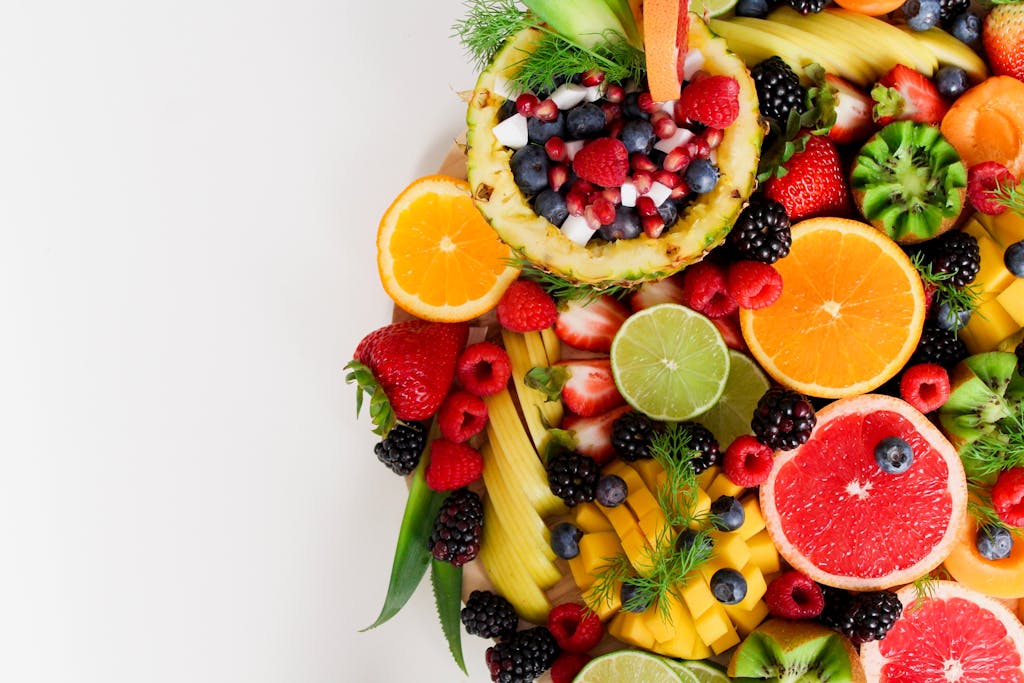 Hi there! Welcome to your Wellness journey. Colorful flat lay of assorted tropical fruits including pineapple, berries, and citrus.