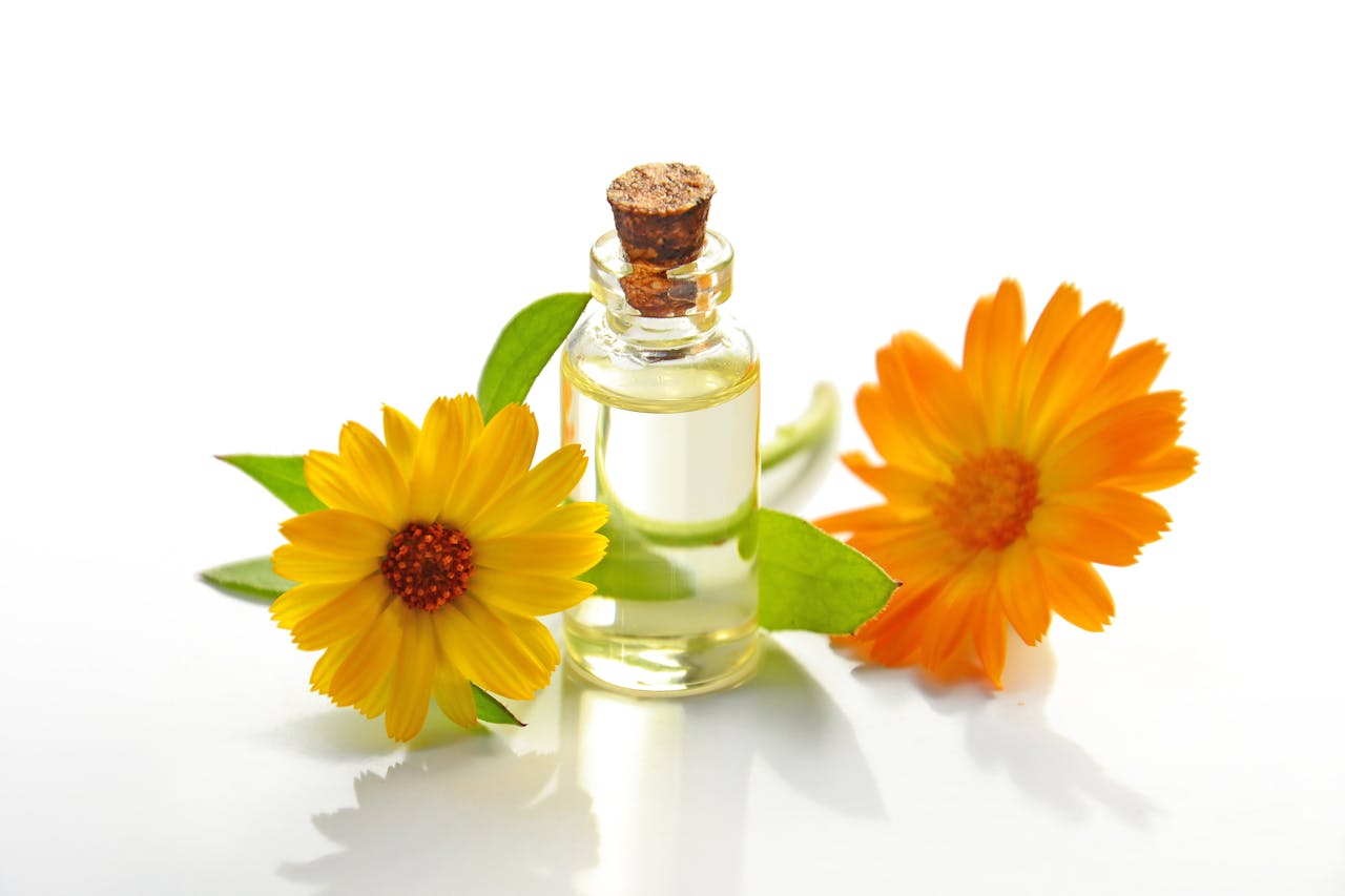 services-03 A glass bottle of aromatic oil with chamomile flowers on a white background.